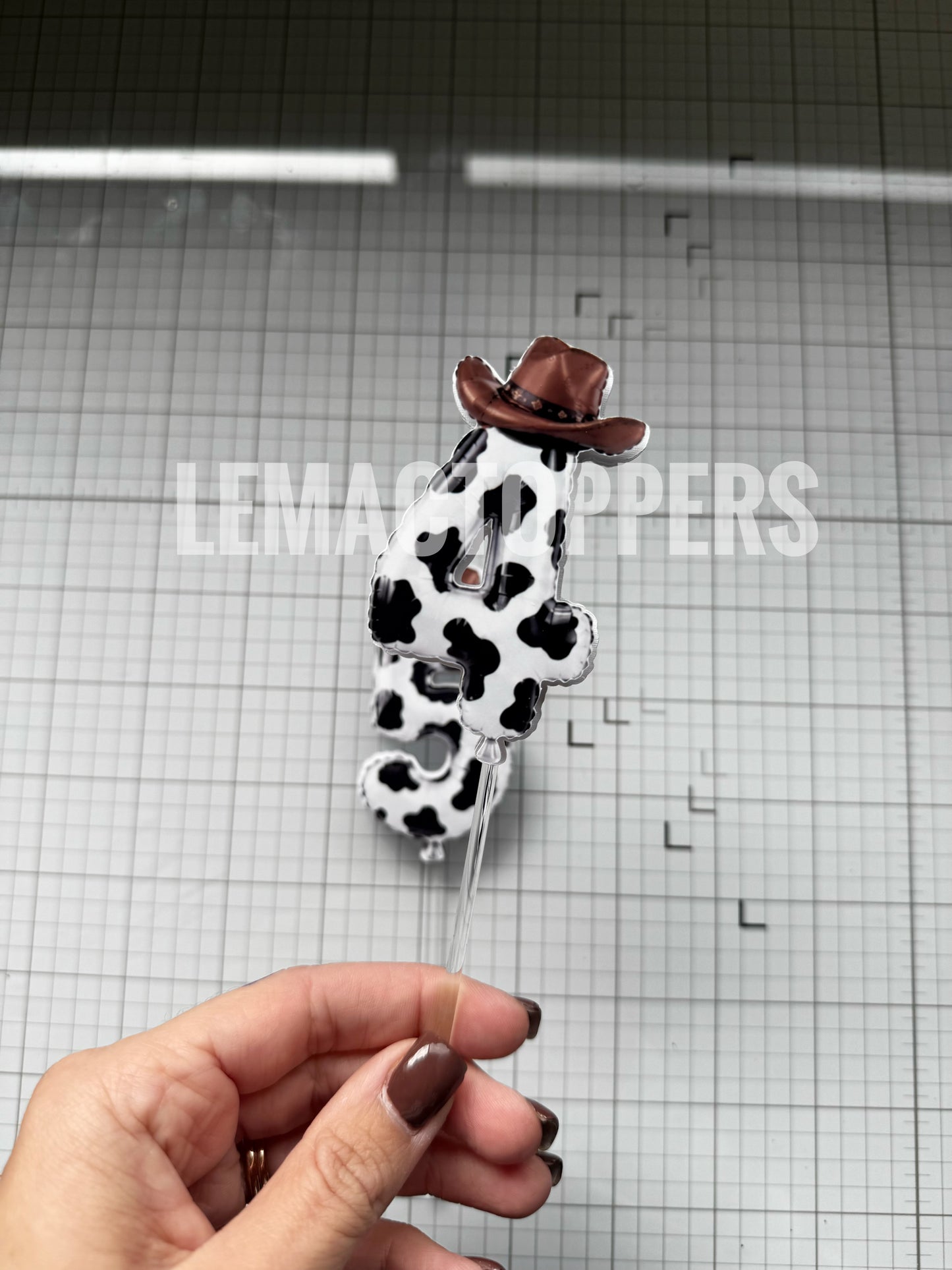 A Cow-Print Cake Topper That looks like a balloon number, with a brown cowboy hat