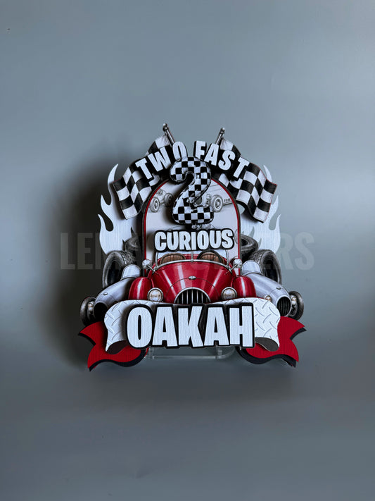 A 3D metal wall sign featuring a red classic race car, checkered flags, flames, and bold text reading 'TWO FAST CURIOUS OAKAH' on a gray background.